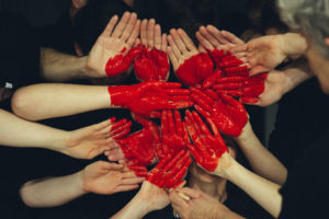 painted hands come together to create a red heart
