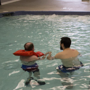 individual and staff swim together at community pool