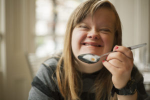girl smiling while bringing a spoon of food toward her mouth