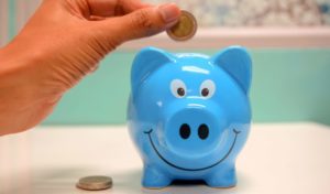 photo of blue piggy bank, person dropping a coin in