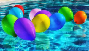 photo of pool with colorful baloons floating on the water