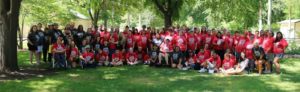 photo of the Otero team, most wearing red t-shirts on a green lawn surrounded by trees