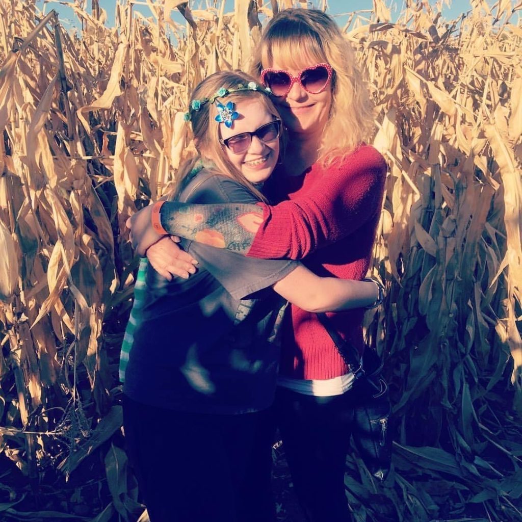 Maya and Rendi, mother and daughter, hugging in a corn field 